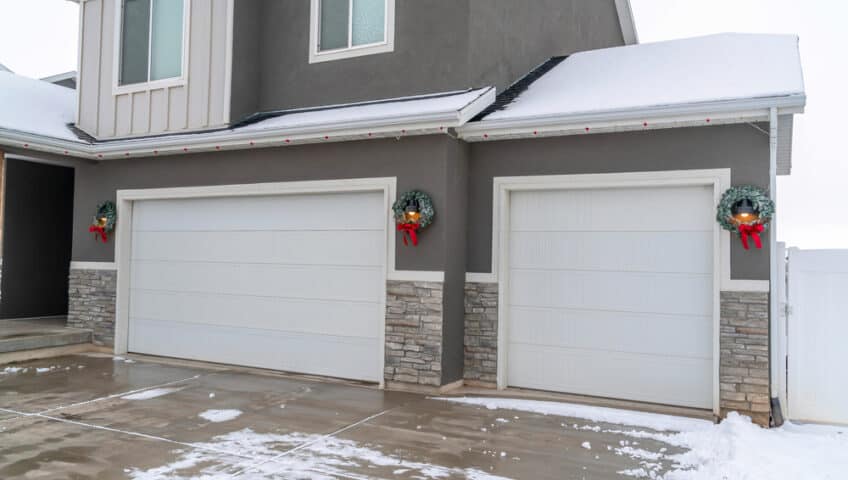 white steel insulated garage doors on a home covered in snow