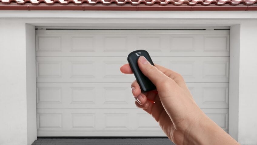a woman's hand using a garage door remote, trying to get a garage door that won't close to move